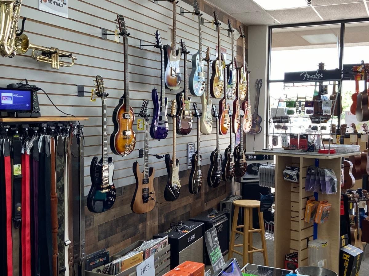 Electric guitars, a bass, and brass instruments on the wall near the front window