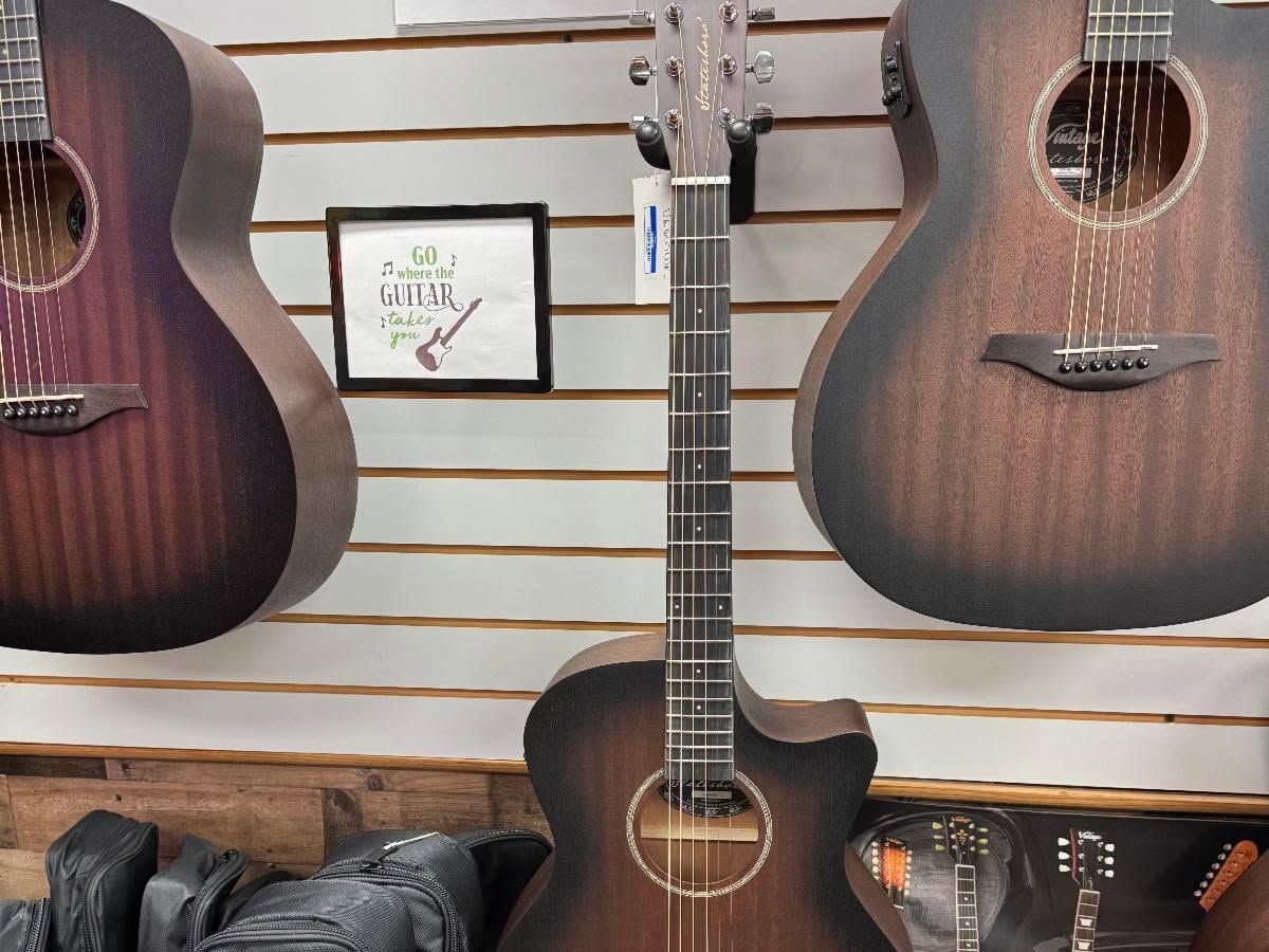 Close view of three satin finish acoustic cutaways hanging side by side