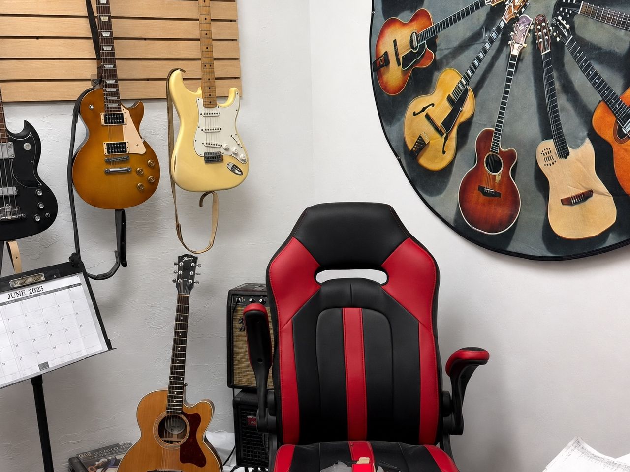 Lesson room corner with a bass, a Les Paul, and a Strat on the wall