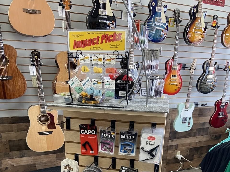 Picks, capos, slides, and strings on the accessory stand in the middle of the store