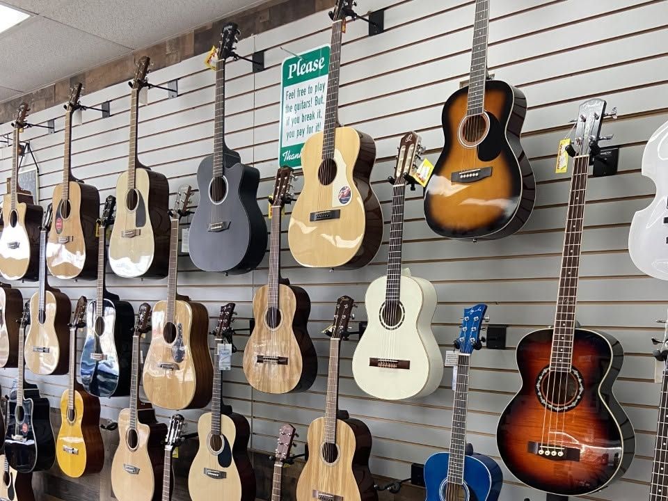 Acoustic guitars and a violin shaped bass hanging beside the front window