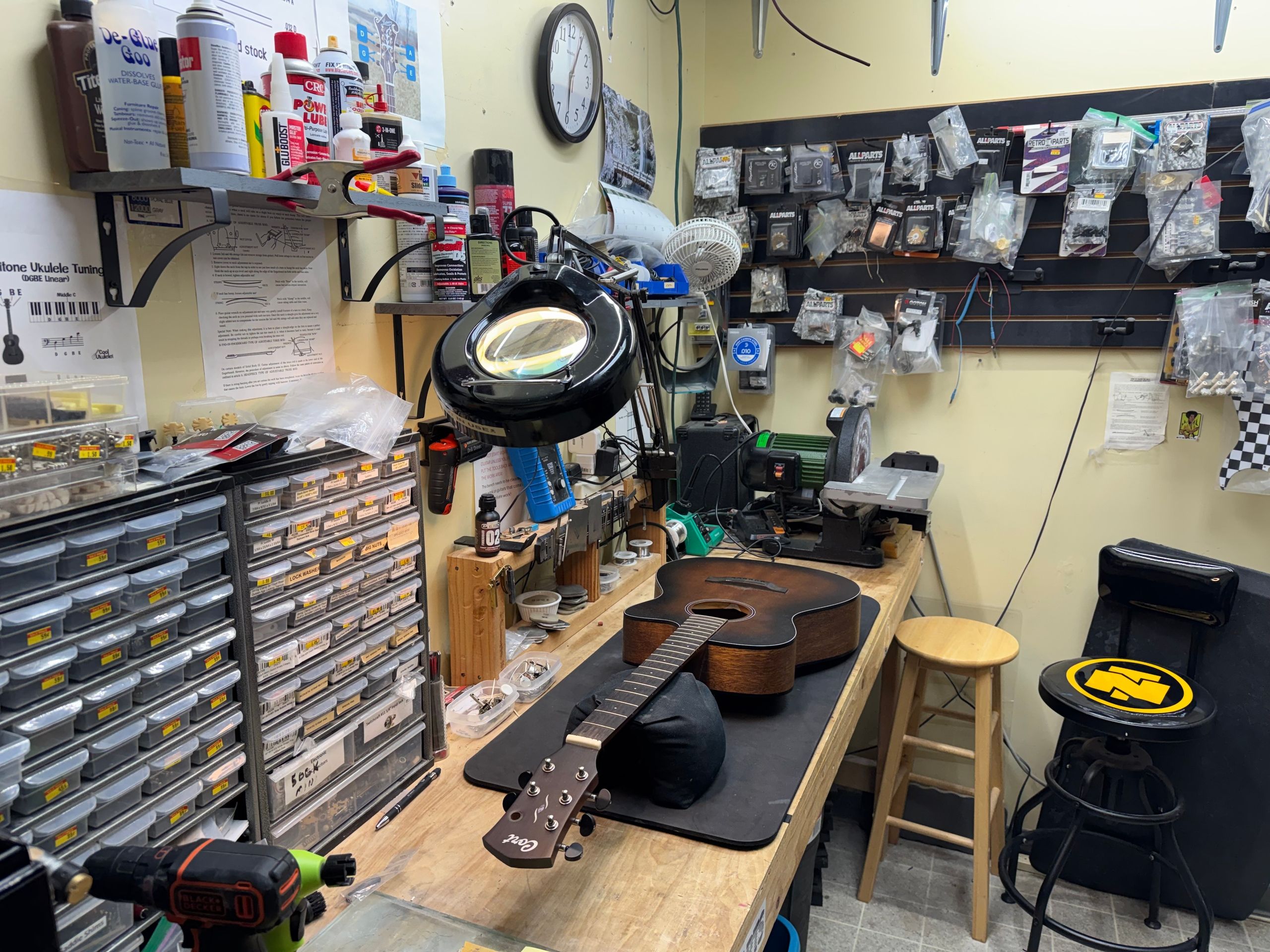 Guitar resting on the bench mat under the magnifier lamp during a setup