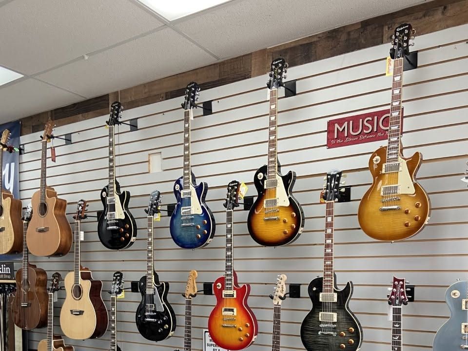 Les Paul and Telecaster style electrics hanging above a rack of shop t-shirts