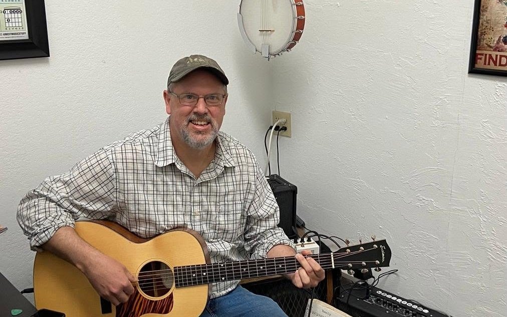 Guitar teacher seated with an acoustic guitar in a lesson room at The Guitar Shop