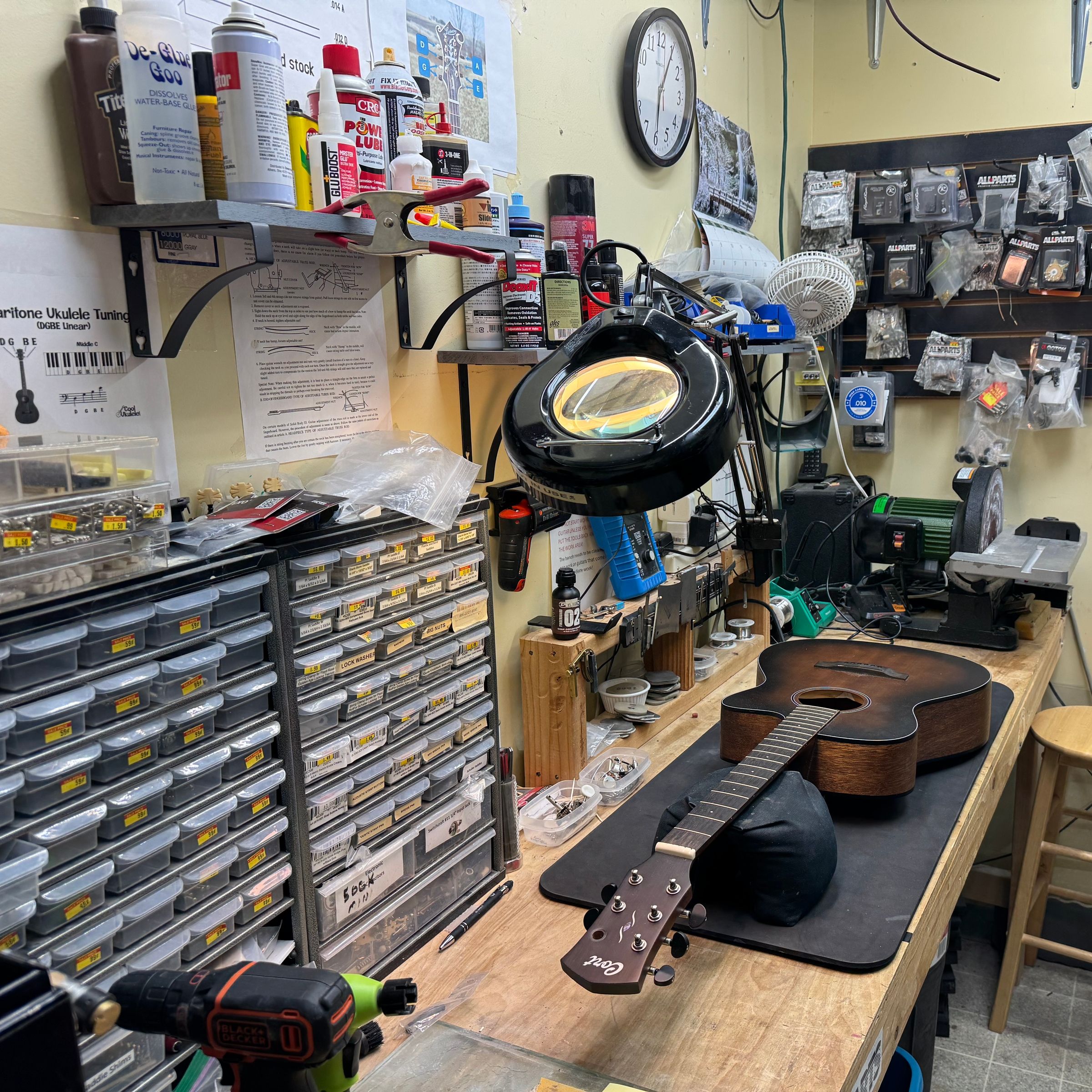 Acoustic guitar on the repair bench beside the parts drawers and bench tools