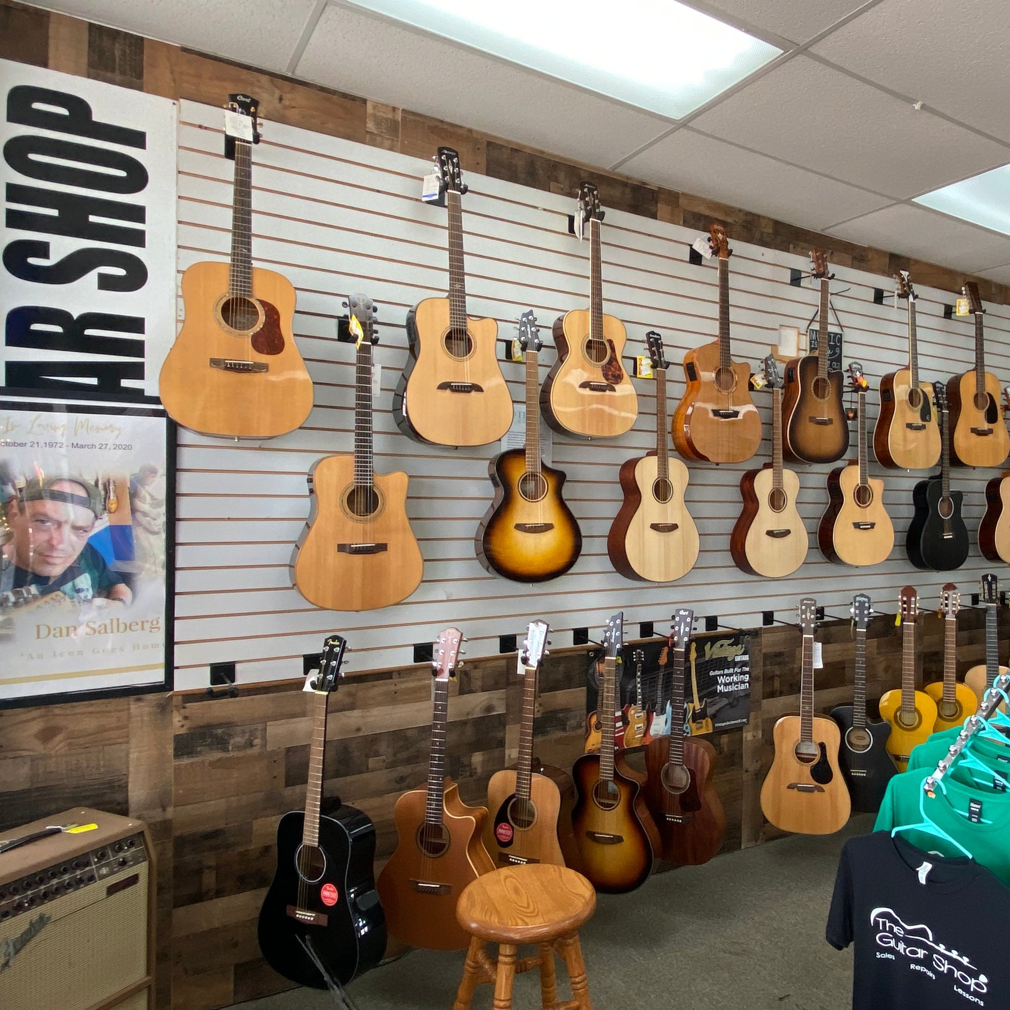 Two rows of acoustic guitars hanging on the slatwall above reclaimed wood panelling
