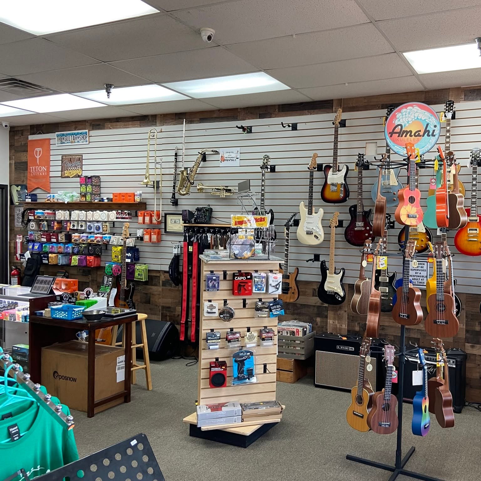 Electric guitars, ukuleles, and brass instruments on the wall by the accessory stand