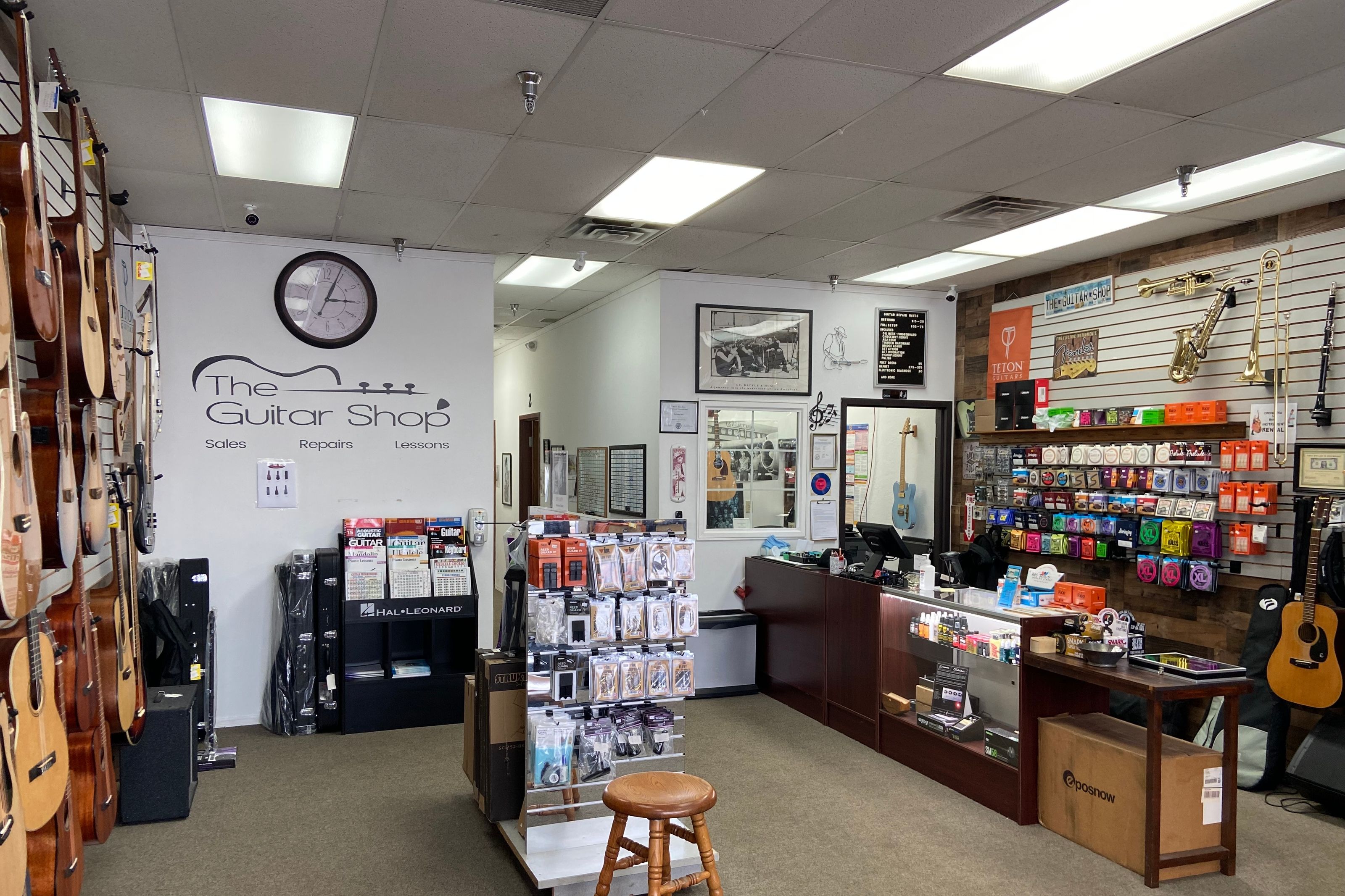 The Guitar Shop counter under the painted wall logo, with the string wall and accessory racks alongside