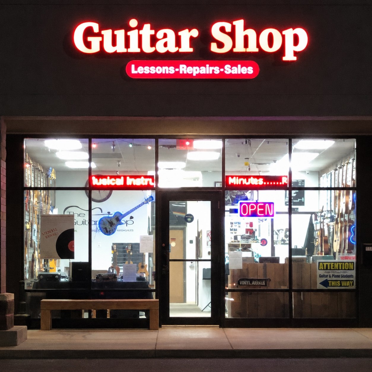 The Guitar Shop storefront lit up at night with the neon sign and open sign glowing