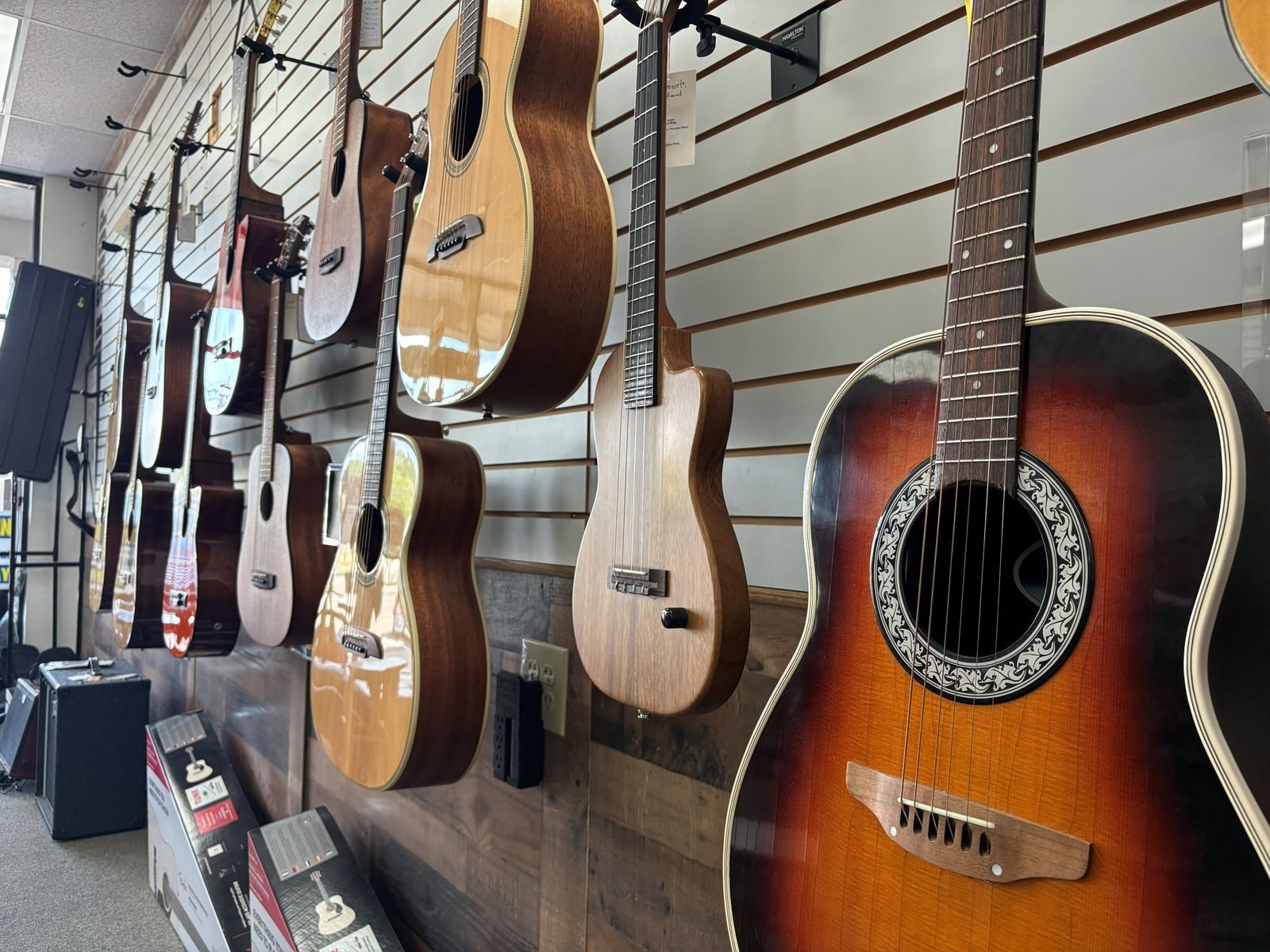 Acoustic row with a sunburst Ovation roundback hanging among the flat-tops