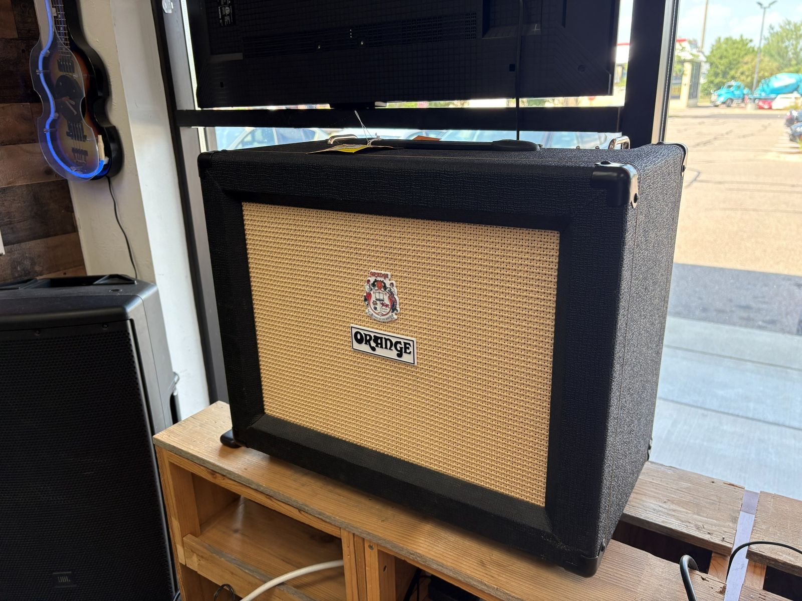 An Orange combo amp on the reclaimed wood bench beside the pedal board