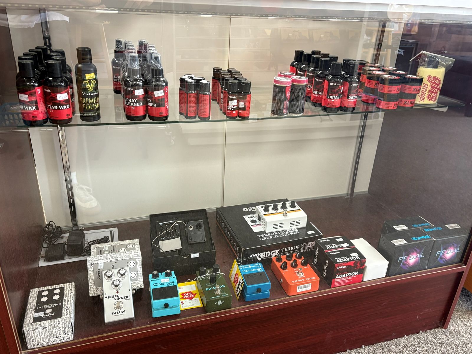 The glass counter case with effects pedals, tuners, polish and setup supplies
