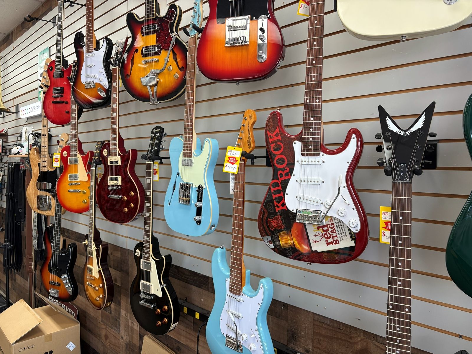 Close view of the electric wall: a cherry Les Paul, a sunburst semi-hollow and a sky-blue Telecaster