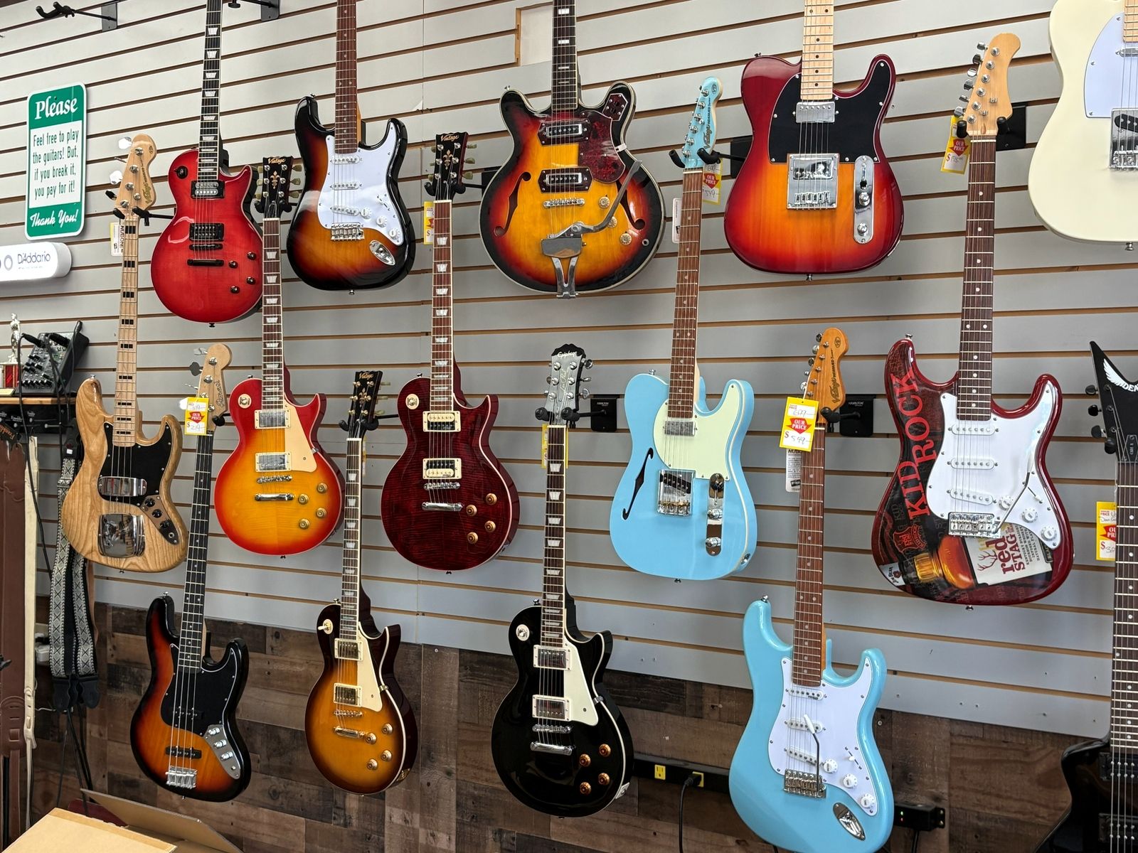 The electric wall: Les Pauls, Telecasters, a sunburst semi-hollow and basses on slatwall
