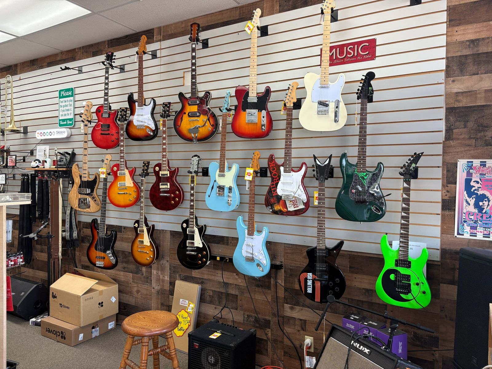 The full guitar wall from electrics to acoustics, with the stool below