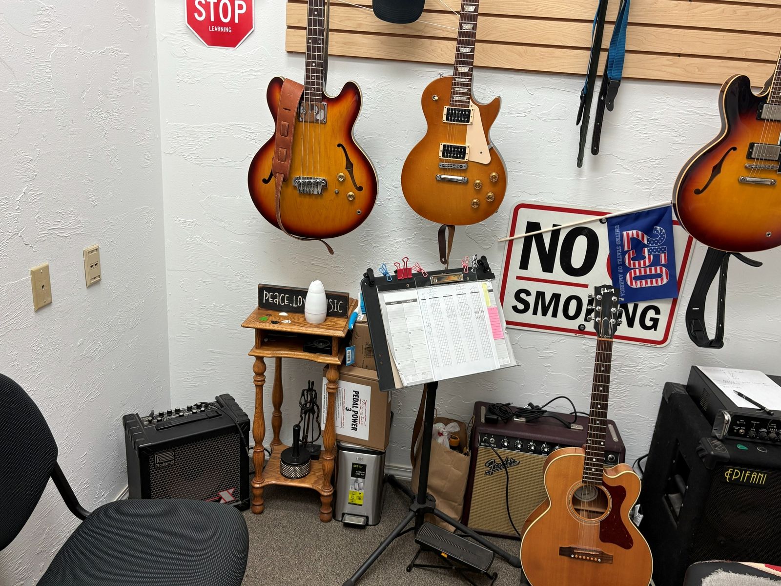 A lesson room set up with an amp, music stand and guitars against the wall