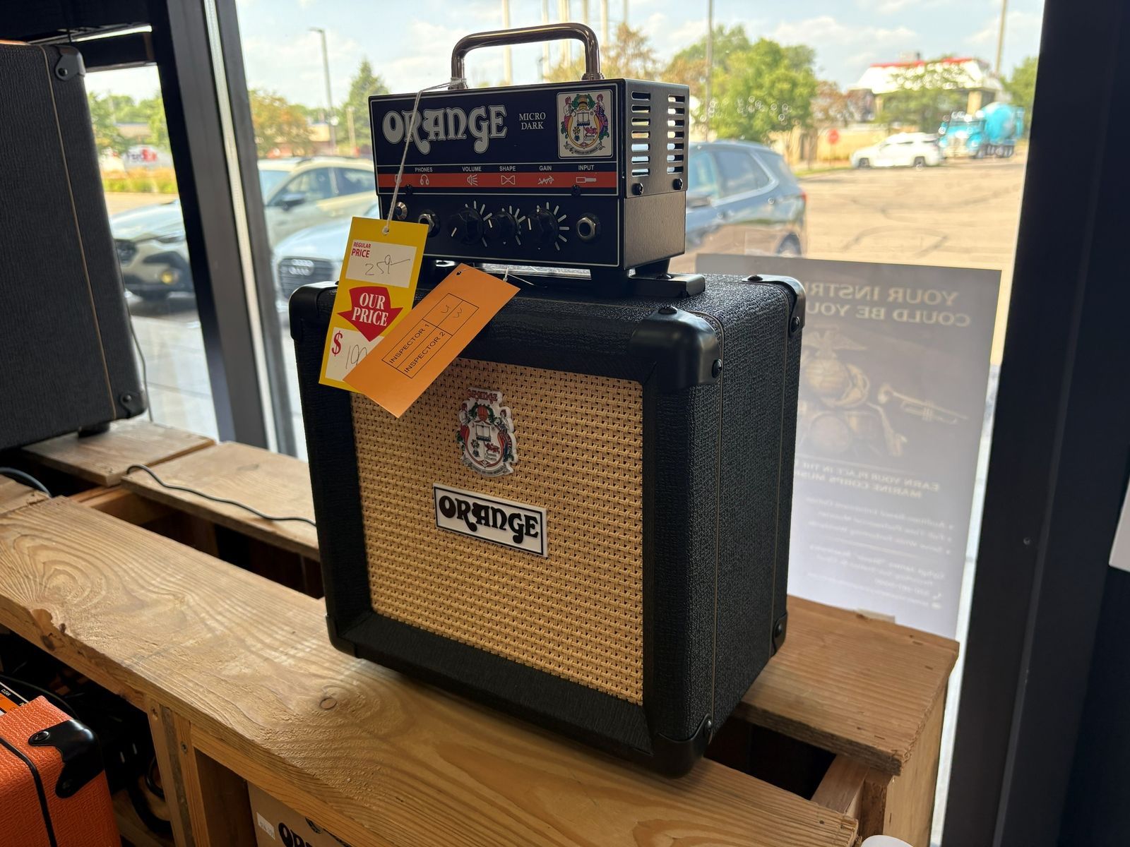 An Orange amp head on its cab on the reclaimed wood bench by the window