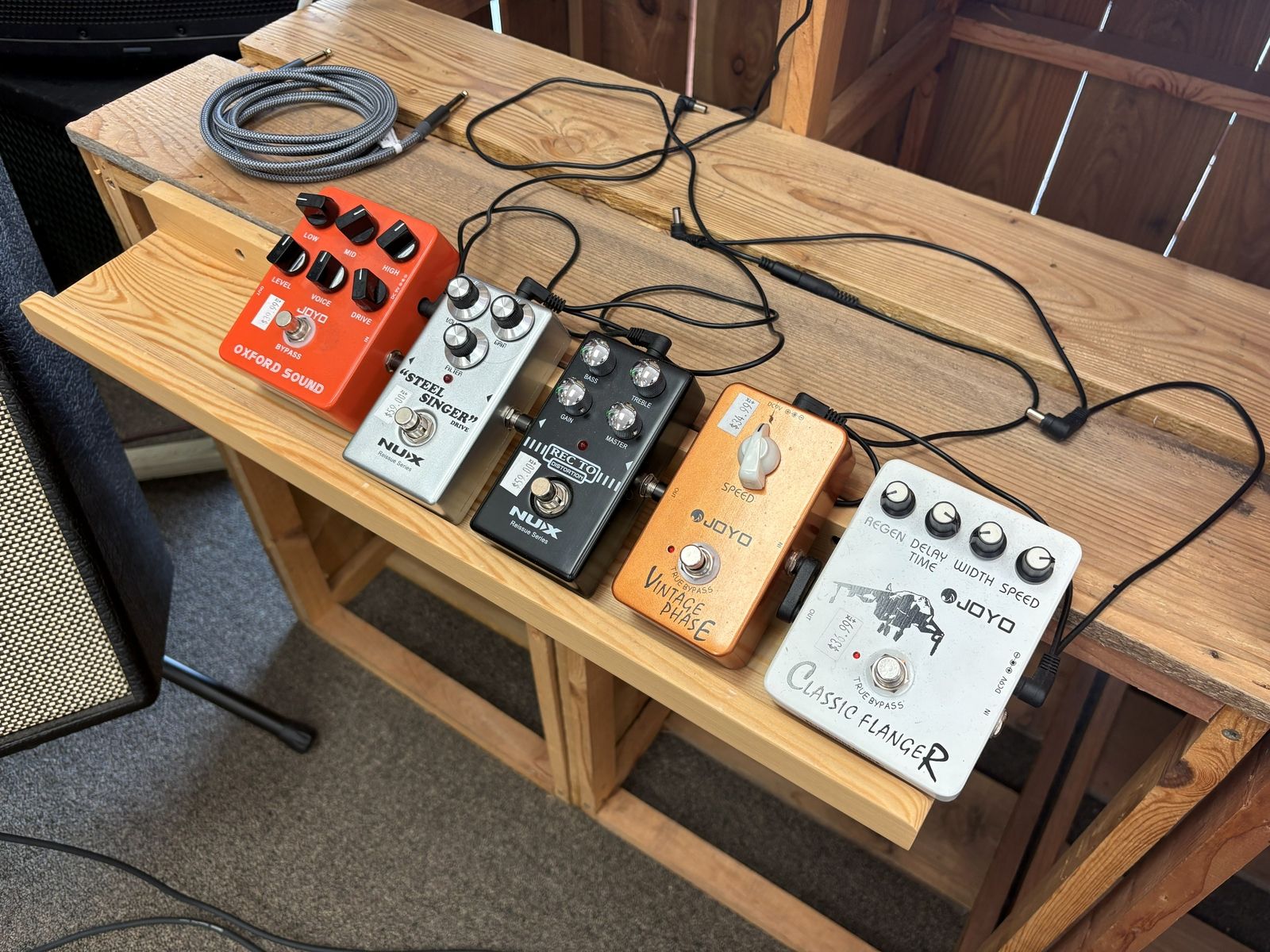 A row of effects pedals wired up on the wood bench, flanger to vintage drive