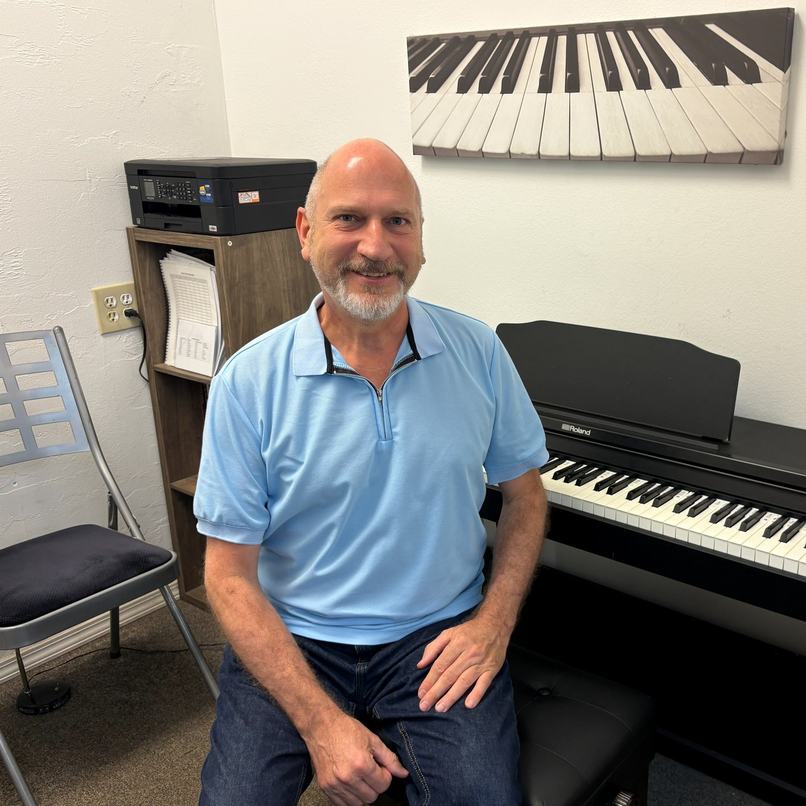 Tim at the Roland digital piano in the lesson room, under the keyboard artwork